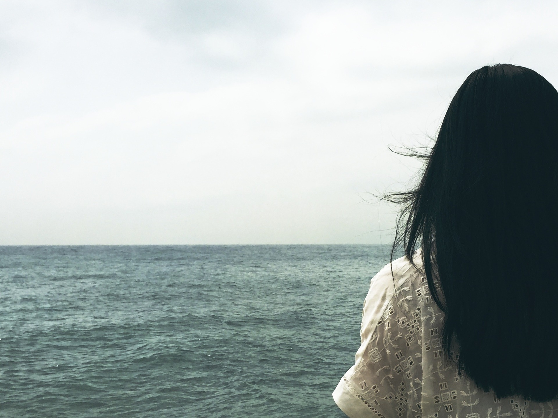 woman starting out to sea in despair